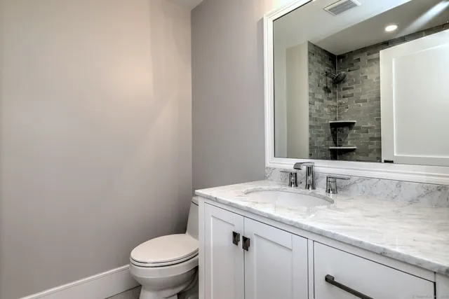 a bathroom with a granite countertop toilet a sink and a mirror