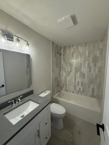 a bathroom with a bathtub shower sink vanity mirror and toilet