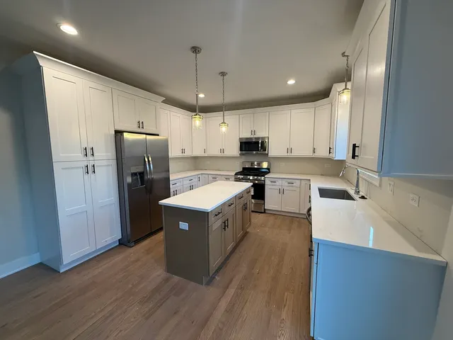 a kitchen with kitchen island a sink a center island stainless steel appliances and cabinets