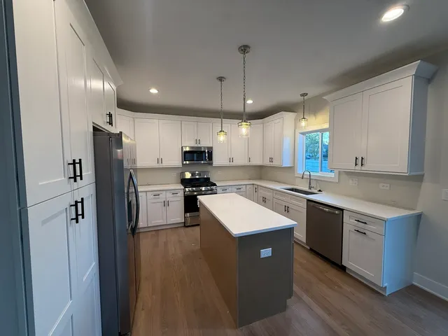 a kitchen with kitchen island a sink a center island stainless steel appliances and cabinets