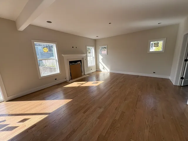 a view of an empty room with window and wooden floor