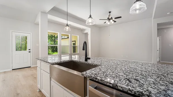 a kitchen with a sink granite counter top a window and chandelier