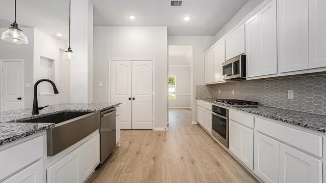 a kitchen with granite countertop a sink stove and cabinets