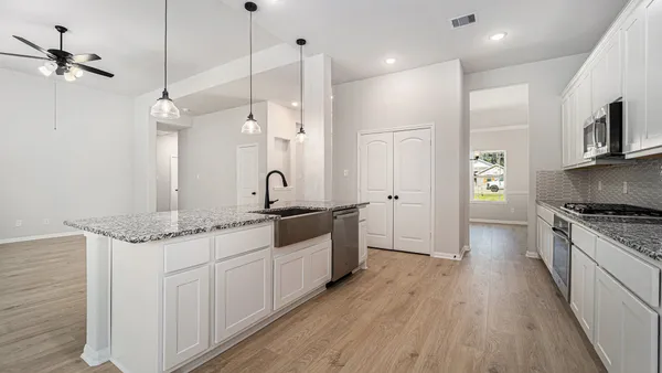 a large kitchen with stainless steel appliances granite countertop a lot of counter space and wooden floor