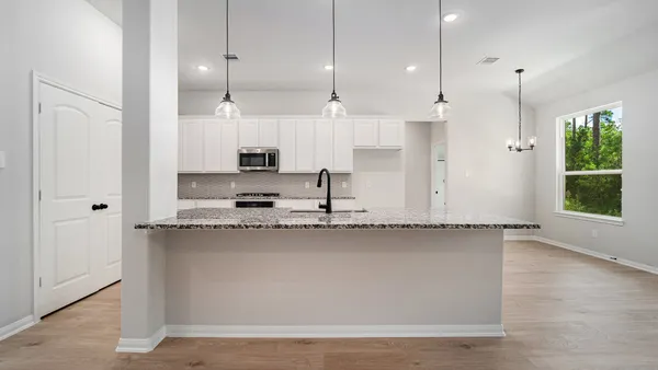 a view of a kitchen with kitchen island a sink wooden floor and a window