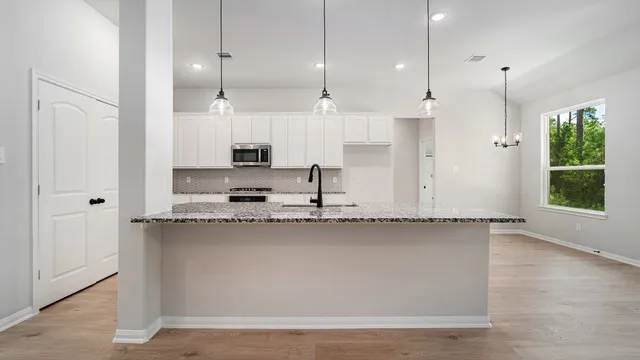 a view of a kitchen with kitchen island a sink wooden floor and a window