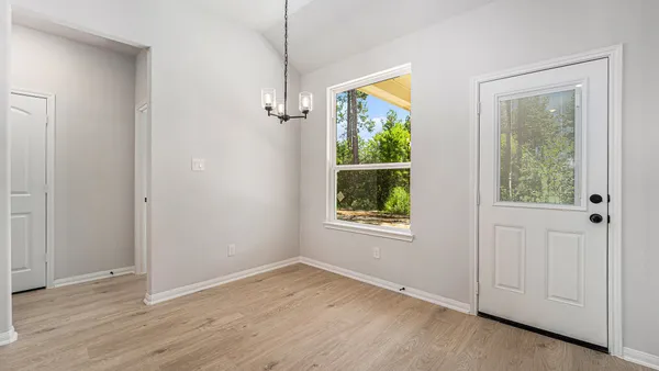 an empty room with wooden floor mirror and windows