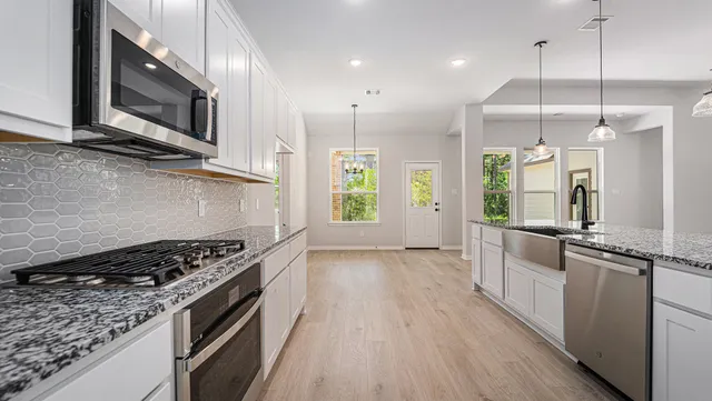 a kitchen with stainless steel appliances granite countertop a stove and a wooden floors