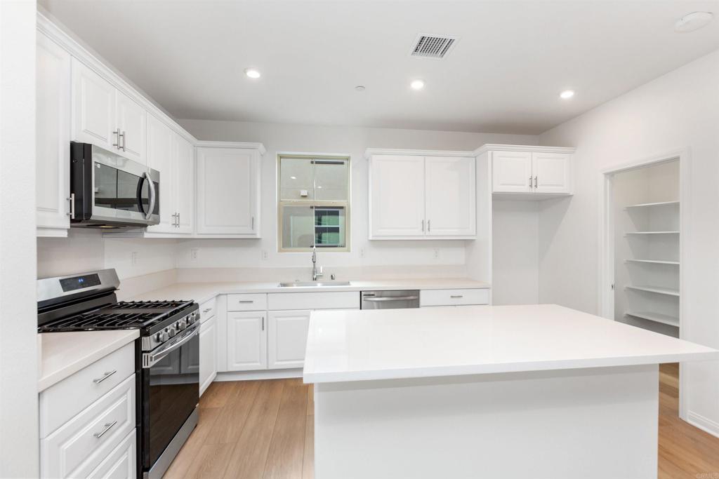 1532 Redbud Way Oceanside, CA 92056 - Photo 6 of 40 a kitchen with stainless steel appliances a sink a stove a refrigerator cabinets and a window