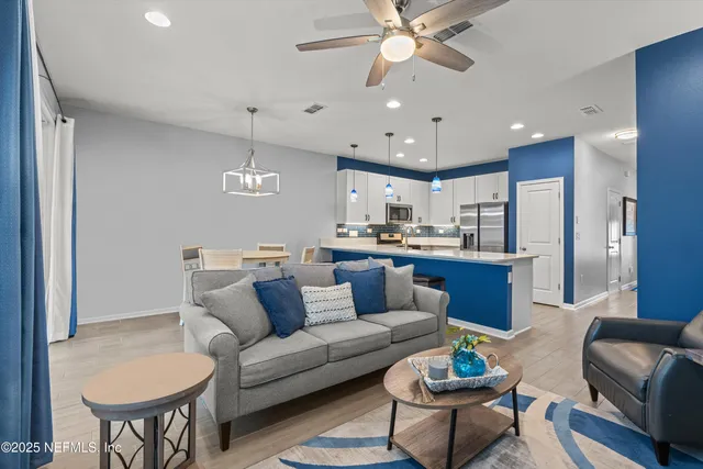 a living room with furniture kitchen view and a chandelier