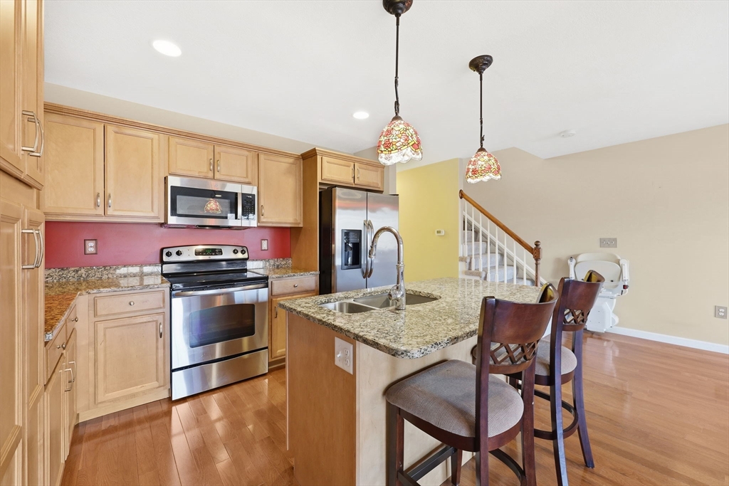 353 Fuller Street, Unit 8 Ludlow, MA 01056 - Photo 7 of 41 a kitchen with stainless steel appliances granite countertop a stove top oven a refrigerator a kitchen island a dining table and chairs with wooden floor