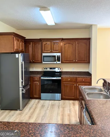 a kitchen with stainless steel appliances granite countertop a refrigerator stove and sink