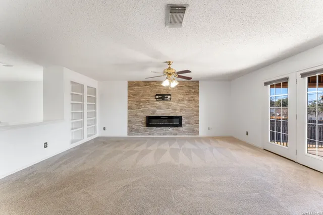 a view of an empty room with a fireplace and a window