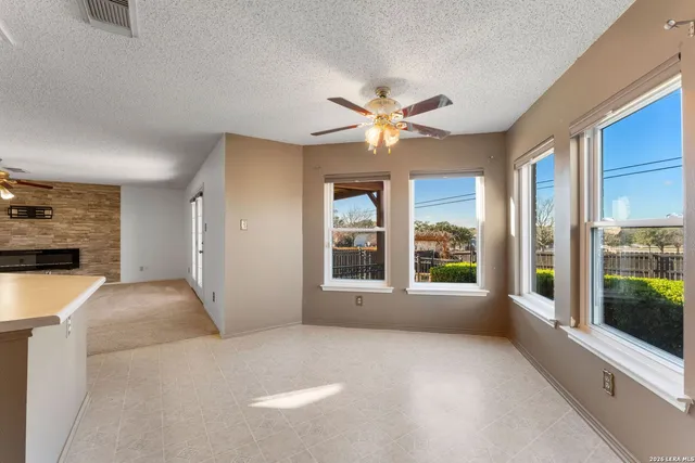 a view of an empty room with a window and a kitchen