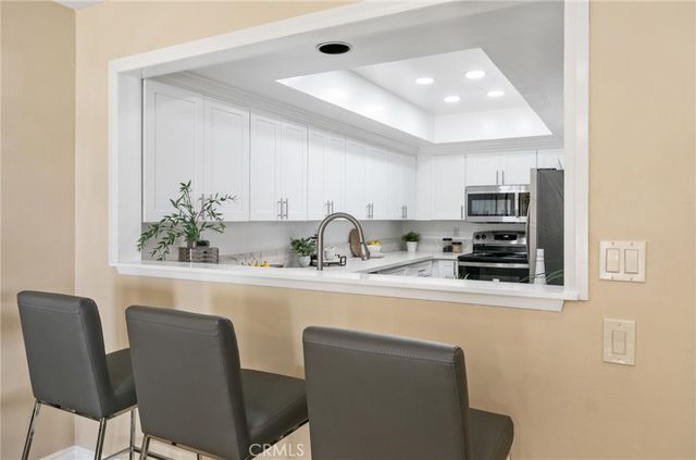 a kitchen with stainless steel appliances a dining table chairs and a refrigerator