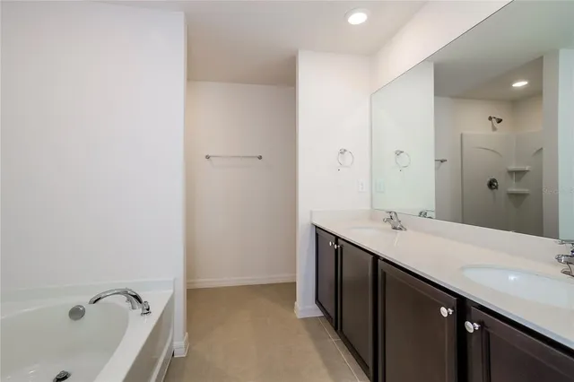 a bathroom with a tub sink double vanity and tub