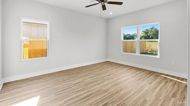 a view of an empty room with a window and wooden floor