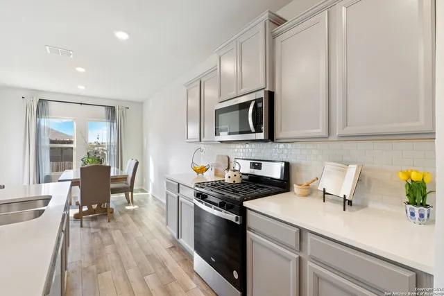 a kitchen with granite countertop a sink a stove top oven and cabinetry