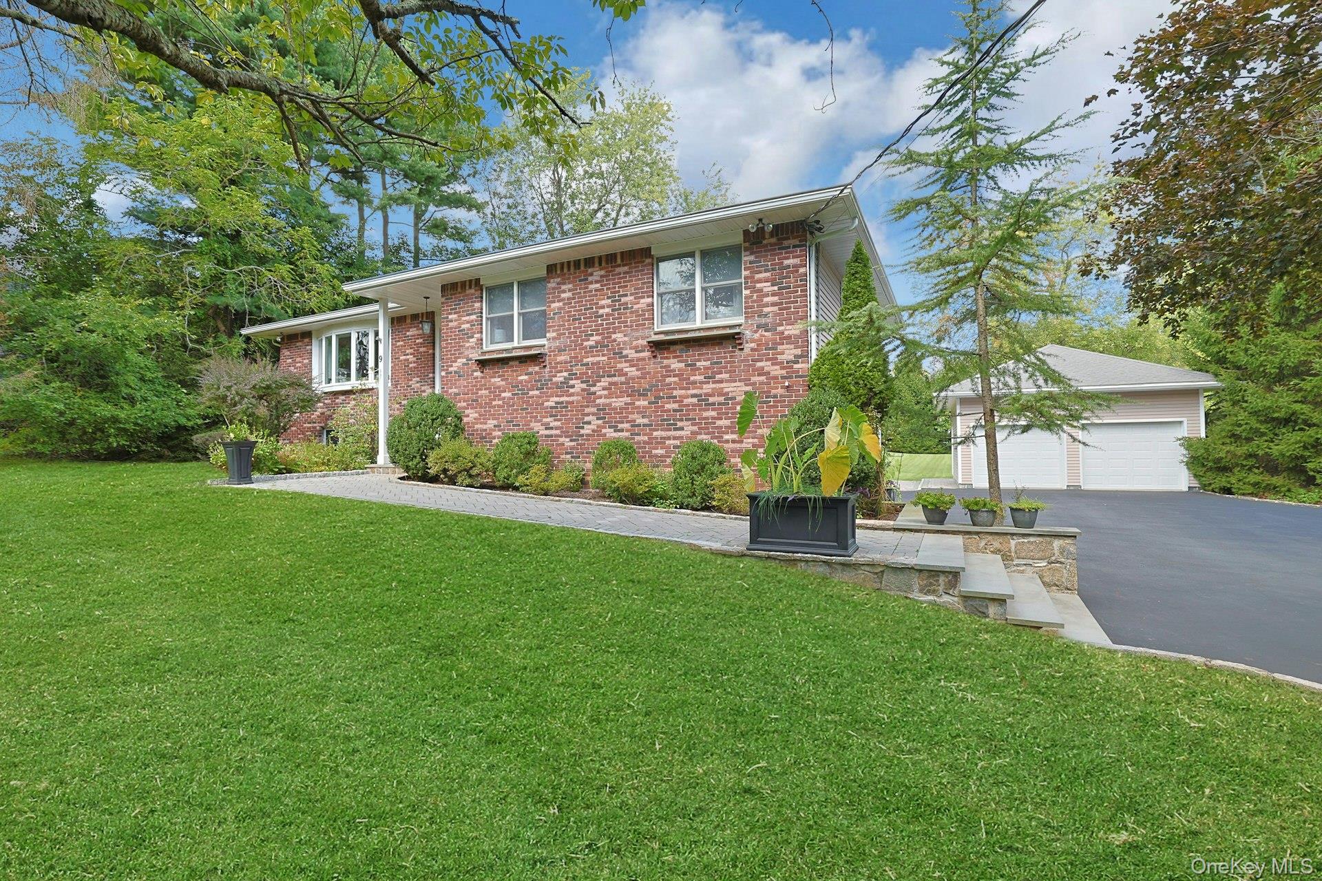 9 Stonegate Road Valhalla, NY 10595 - Photo 3 of 42 Brick exterior with multiple windows, leading to a paved driveway and a two-car garage