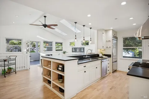 a kitchen with stainless steel appliances granite countertop a sink a stove and a wooden floors