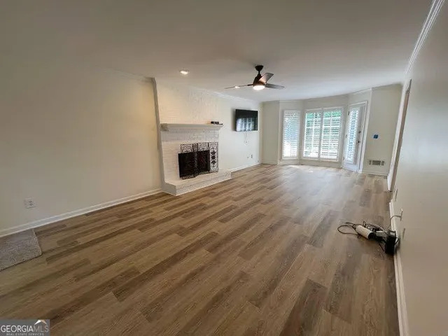 an empty room with wooden floor fireplace and windows