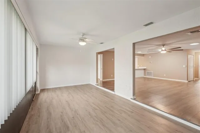 an empty room with wooden floor and a ceiling fan