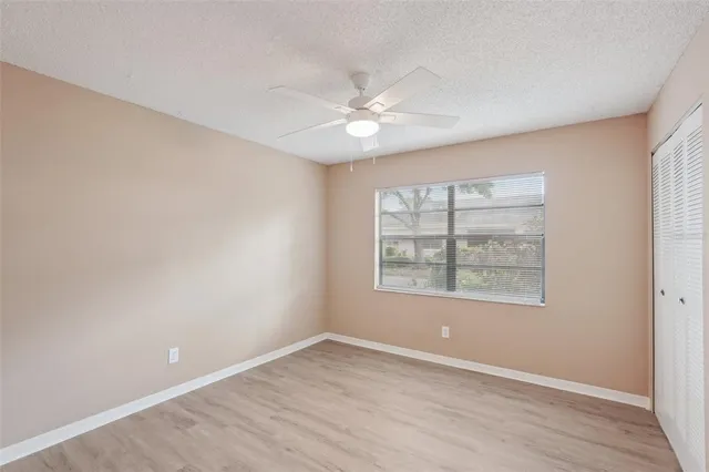 a view of an empty room with a window and wooden floor