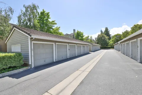 a view of a house with a small yard and a large parking space