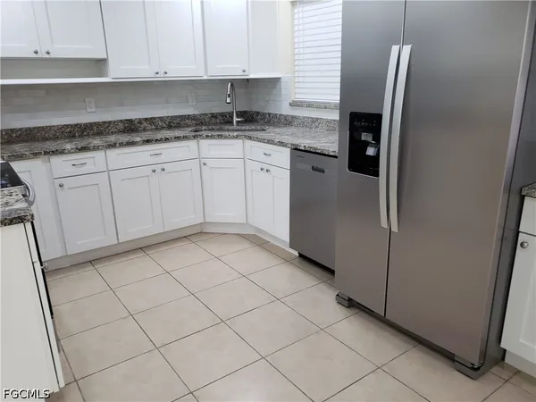 a kitchen with granite countertop white cabinets and stainless steel appliances