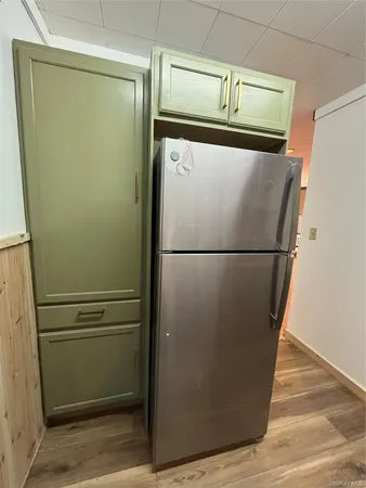 a close view of a refrigerator in kitchen and an empty room