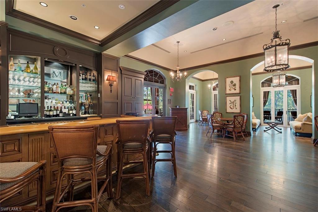 14906 Bellezza Lane Naples, FL 34110 - Photo 25 of 33 a dining hall with stainless steel appliances granite countertop a couch and a dining table with wooden floor
