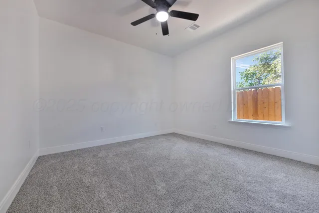 an empty room with windows and ceiling fan