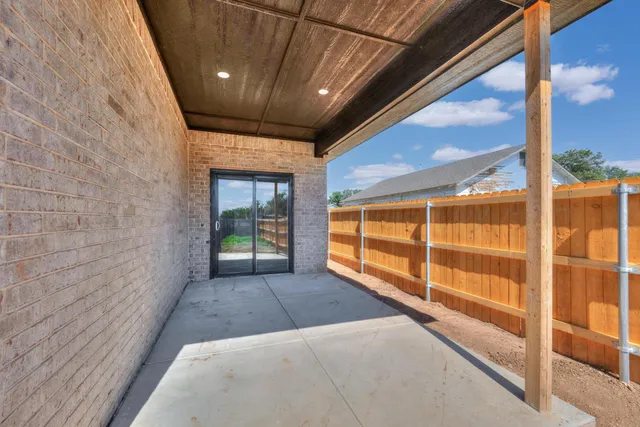 a view of an empty room with wooden floor and windows