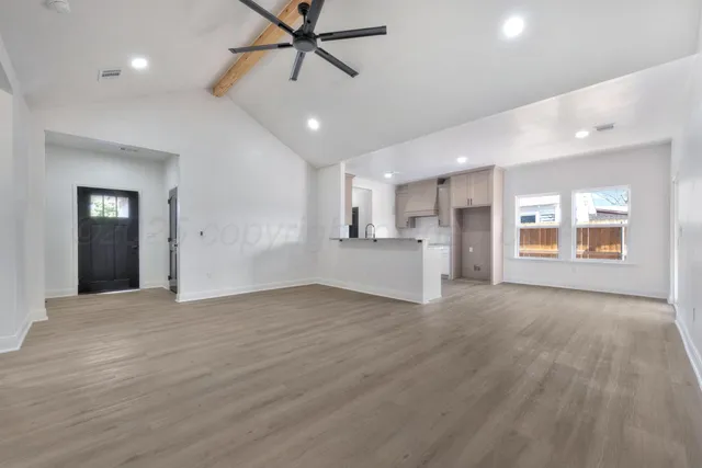 a view of an empty room with a window and wooden floor