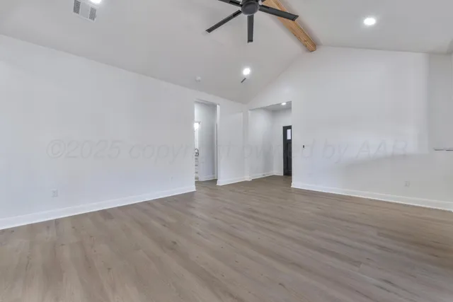 an empty room with wooden floor ceiling fan and window