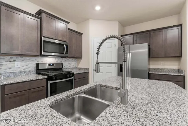 a kitchen with granite countertop a refrigerator and a sink