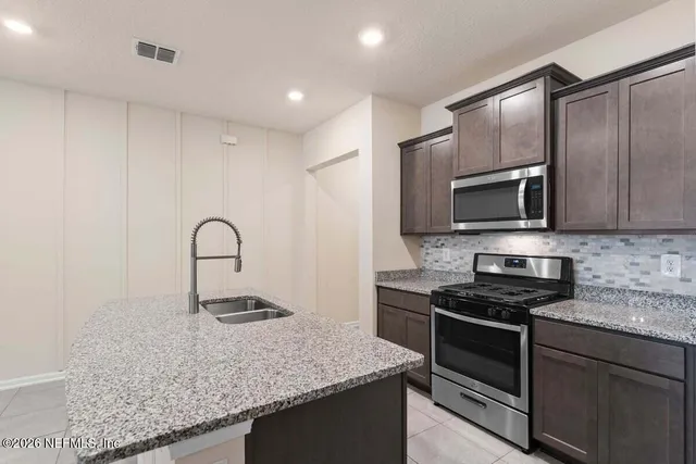 a kitchen with granite countertop a sink and stainless steel appliances