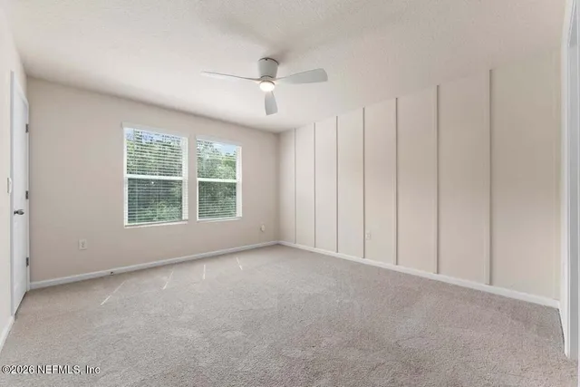 an empty room with windows closet and chandelier fan