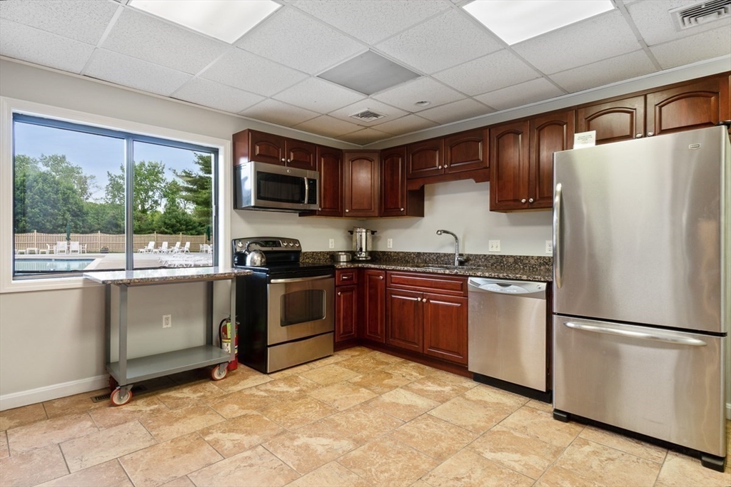 8 Ledgewood Way, Unit 20 Peabody, MA 01960 - Photo 32 of 37 a kitchen with granite countertop a refrigerator a sink a stove top oven and cabinetry