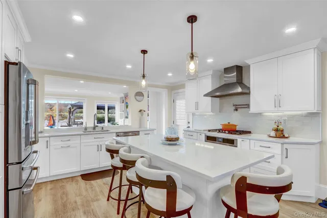 a kitchen with stainless steel appliances granite countertop a sink a stove a dining table and chairs with wooden floor