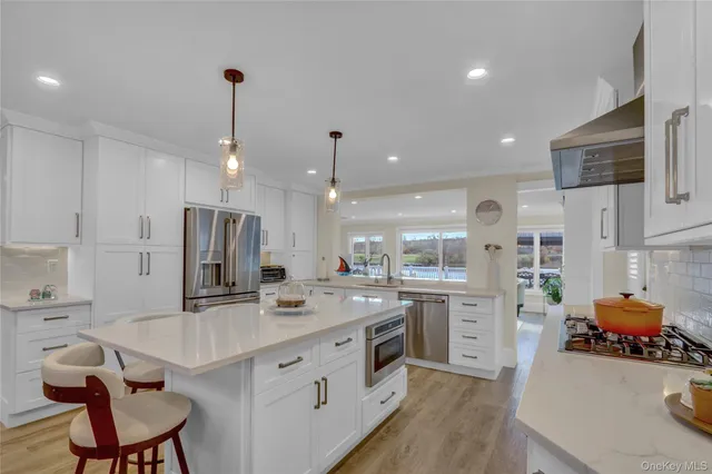 a kitchen with stainless steel appliances kitchen island granite countertop a sink and a refrigerator