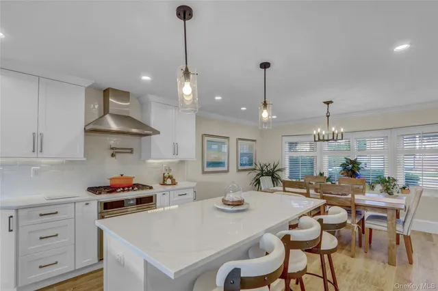 a kitchen with a dining table chairs stove and white cabinets
