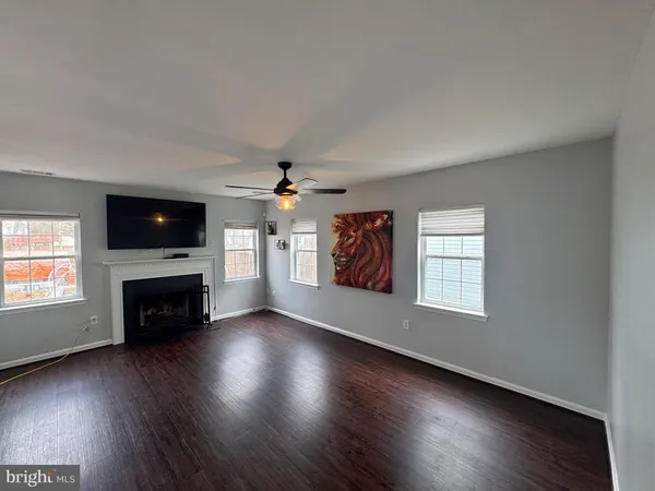 an empty room with windows a fireplace and wooden floor