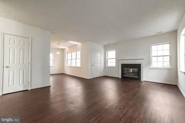 an empty room with wooden floor fireplace and windows