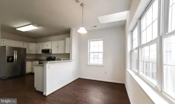 a kitchen with stainless steel appliances a stove top oven a sink a refrigerator a window and white cabinets