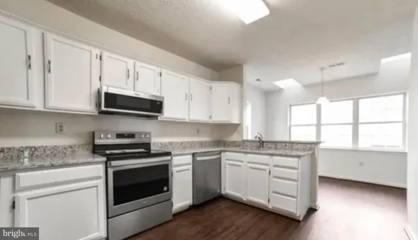 a kitchen with stainless steel appliances granite countertop white cabinets a stove a sink and a microwave