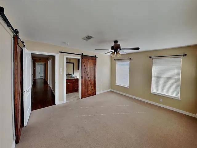 a view of a big room with windows and chandelier fan