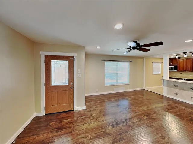 a view of empty room with wooden floor and fan