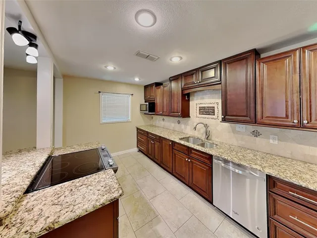 a kitchen with granite countertop sink stainless steel appliances and cabinets