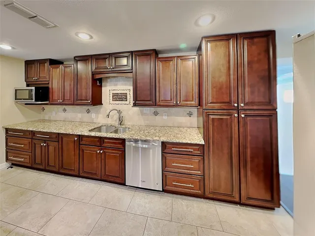 a kitchen with stainless steel appliances granite countertop wooden cabinets a sink and dishwasher